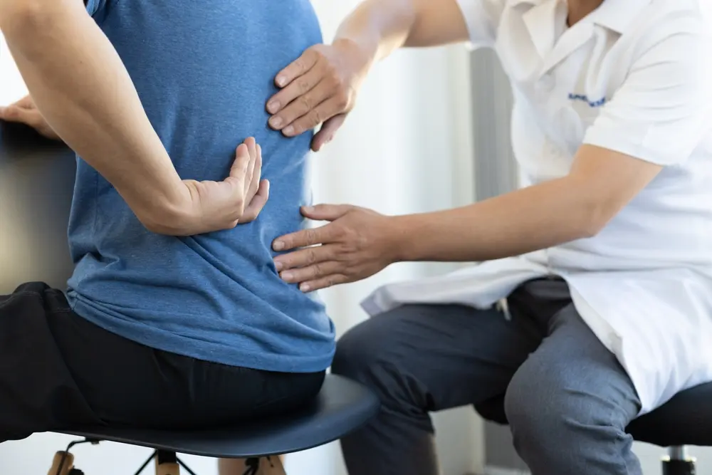 A doctor examining a male patient experiencing back pain, diagnosing the condition to provide proper treatment and care.